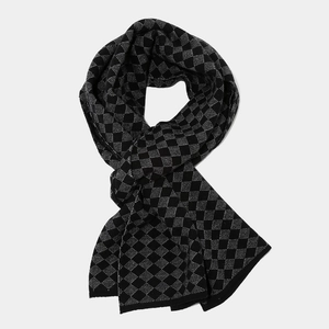 Detail of knitted scarf featuring a classic black and grey diamond checkered pattern