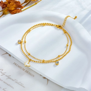 Golden double-layer butterfly pendant anklet with crystals on a white stone tray