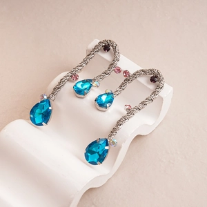 Detail of silver drop earrings with teal crystals and twisted metal texture on stone base