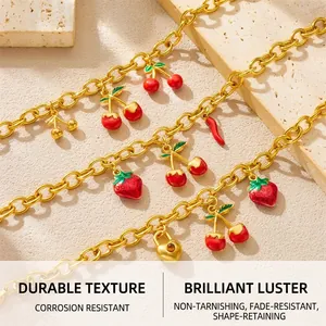 Detail of 18K gold plated chain bracelets with red cherry and heart lock pendants