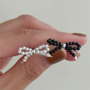 Macro shot of handmade black and white beaded bow earrings featuring metallic accents