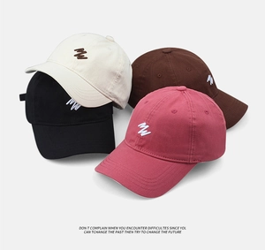 Detailed view of four cotton baseball caps in cream, brown, black and rose pink colors