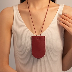 Detail of burgundy pebbled leather necklace pouch with snap button for women