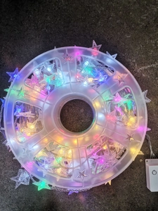 Macro view of colorful star LED string lights wound on a plastic reel for easy storage