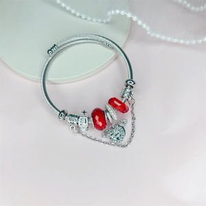 Detail view of silver charm bracelet with red glass beads and heart crown charms