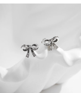 Macro detail of silver bow earrings with sparkling pave-set cubic zirconia crystals