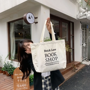 Minimalist cream canvas tote bag with black typography print worn by a model