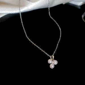 Close-up of three round pearls on a silver stainless steel chain over black velvet