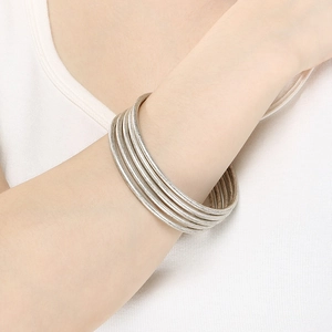 Detail of stacked 3mm matte silver stainless steel bangles on a model's wrist