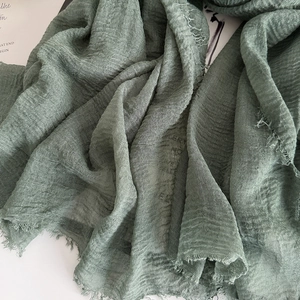 Detailed macro view of the wrinkled texture and raw fringe edges of cotton linen scarf