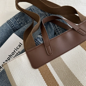 Striped canvas tote bag with brown leather trim and wide shoulder strap for women