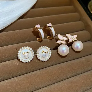 Ensemble de boucles d'oreilles perles cœur et papillon sur un plateau en velours chic