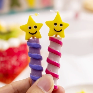 Close-up of star shaped birthday candles with yellow smiley faces and spiral wax stems