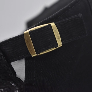 Detail of black cotton ivy cap with vintage bronze metal buckle and adjustable strap