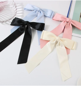 Flat lay of large satin bow hair clips in black, blue, pink, and cream white colors
