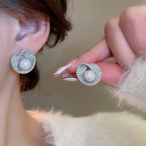 Detailed close-up of a silver pearl stud earring with micro-paved cubic zirconia stones