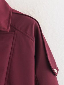 Détail de la veste à col montant bordeaux avec boutons argentés et pattes d'épaule