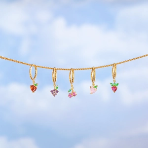 Summer fruit hoop earrings set with colorful cubic zirconia against a clear blue sky