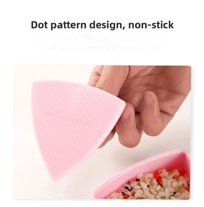 Pink triangular rice ball mold with a non-stick dotted surface for easy sushi making