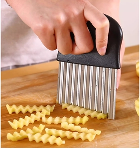 Close-up of wavy stainless steel blade slicing a potato on a wooden board