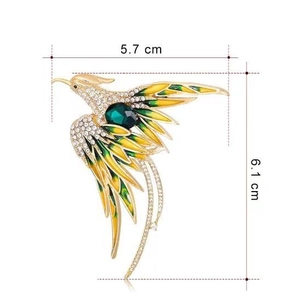 Detail showing a golden phoenix brooch with green enamel wings and white rhinestones