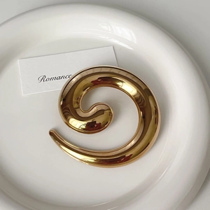 Macro view of spiral golden stainless steel brooch with a high-polished mirror finish