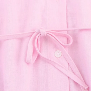 Detailed close-up of pink linen fabric texture with drawstring and resin buttons