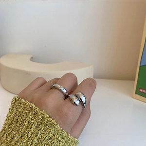Primer plano de anillos minimalistas de latón plateado con circón en el dedo sobre fondo blanco