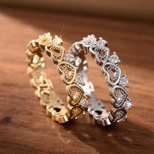 Macro shot of gold and silver openwork heart rings with zircons on dark wood