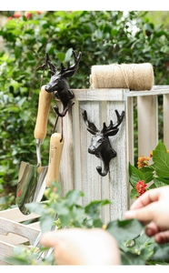 Detail of vintage cast iron deer head hooks on white wood with rustic garden props