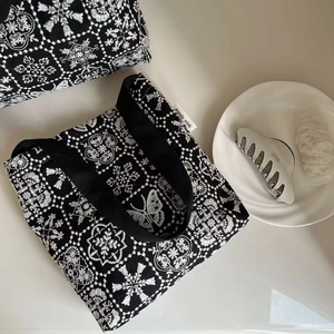 Detail of white butterfly embroidery and simple wish label on black canvas shoulder bag