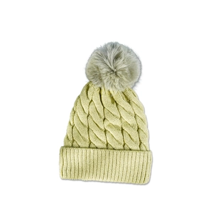 Detailed close-up of beige cable knit beanie featuring thick texture and grey faux fur pom