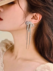 Close-up of dangling bow earrings with sparkling rhinestones and long tassel chains