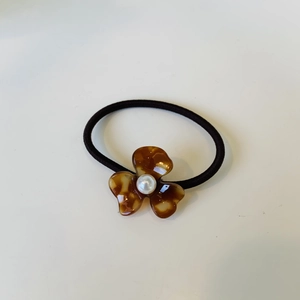 Floral hair tie featuring tortoiseshell acetate petals and a centered white faux pearl
