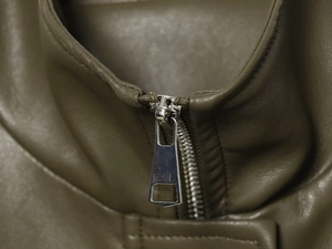 Close-up of durable silver metal zipper on army green faux leather bomber jacket
