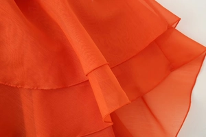 Detailed macro view of vibrant orange layered chiffon fabric with fine stitching