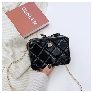 Detail of black PVC jelly bag with quilted texture and golden flower chain buckle