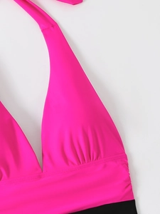 Dettaglio del costume da bagno fucsia e nero con scollatura all'americana e arricciature