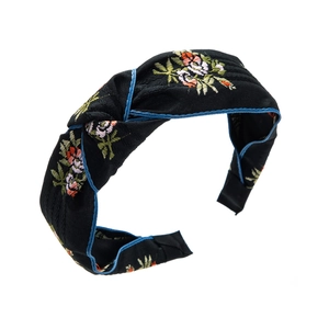 Détail d'un serre-tête noué brodé avec des motifs floraux colorés sur tissu noir épais