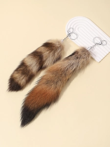 Macro detail of fluffy fox tail keychain with silver metal clip on beige background
