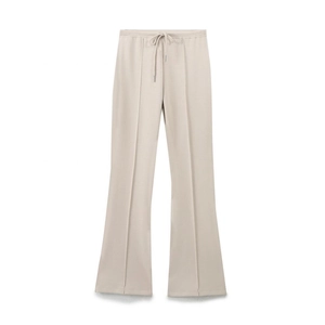 Dettaglio dei pantaloni svasati beige con coulisse in vita e cuciture verticali