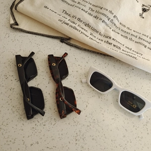 Detailed flat lay of children square sunglasses in black, tortoise, and white colors