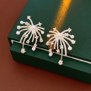 Macro detail of 18K gold plated snowflake earrings with pearls and crystals on green velvet