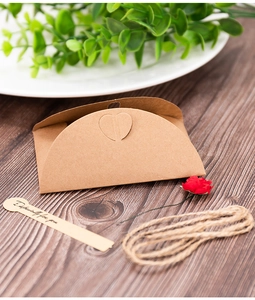 Dettaglio della scatola cuscino in carta kraft con cuore, spago e cartellino in legno