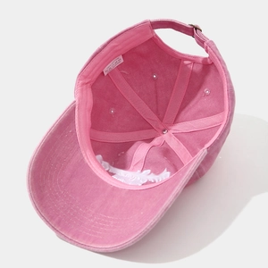 Detail view of pink washed cotton baseball cap interior showing 100% cotton label