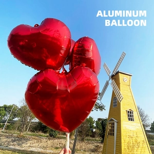 Three 18-inch red heart-shaped aluminum balloons inflated against a bright blue sky background