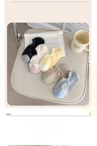 Detailed close-up of polka dot invisible socks in five colors on a textured surface
