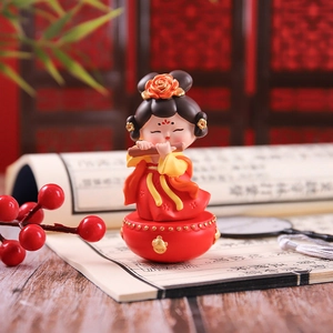 Detail of female tumbler figurine playing flute with red and yellow vintage costume