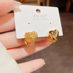 Detail of heart hoop earrings featuring unique textured and polished gold finishes