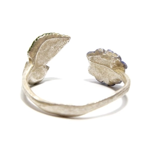 Macro detail of adjustable silver flower and leaf ring with frosted metal texture